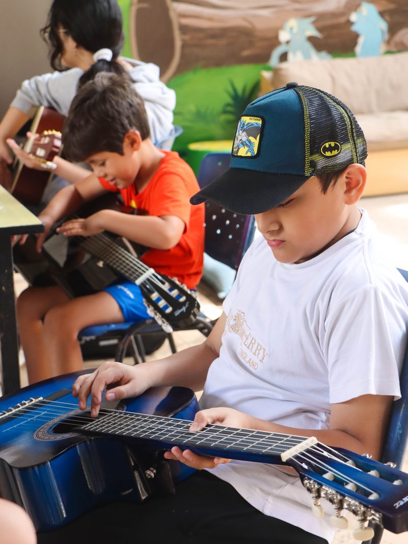 Un alumno practica con su propia guitarra en clase