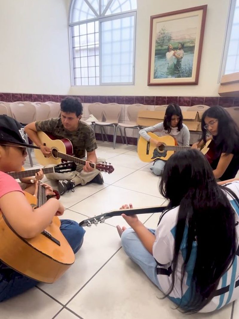Grupo de alumnos practicando guitarra en círculo